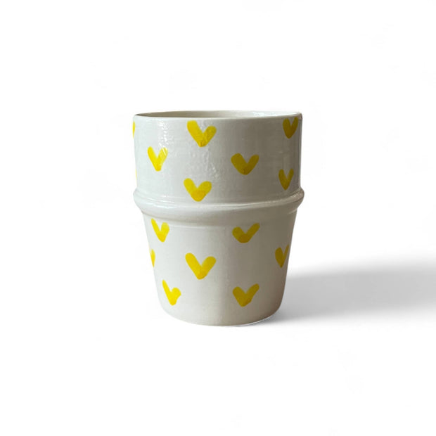 Two white ceramic pots with yellow heart patterns on a white background