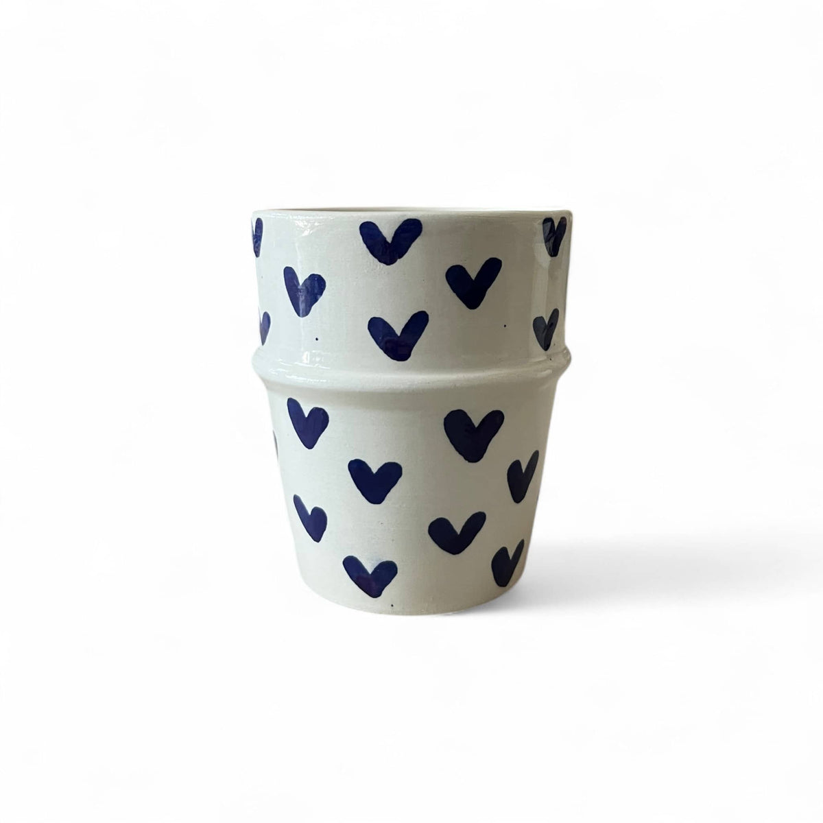 White ceramic cup with blue heart patterns on a white background