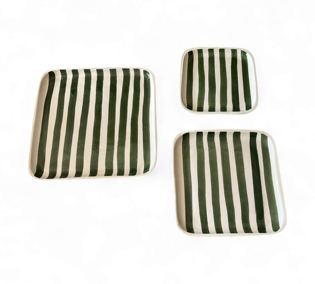 Set of three green and white striped ceramic trays on a white background