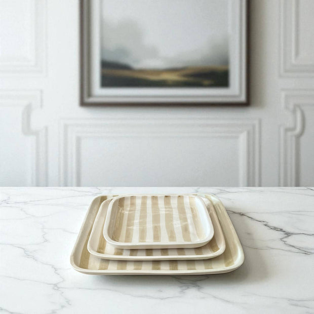 Set of three rectangular ceramic trays with striped pattern on a marble surface.