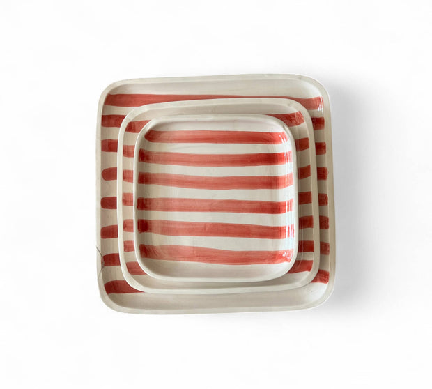 Set of three square ceramic trays with red and white striped pattern on a white background