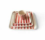 Set of red and white striped ceramic dishes on a white background