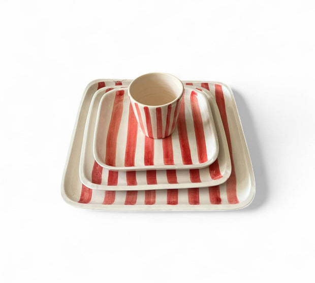 Set of red and white striped ceramic dishes on a white background