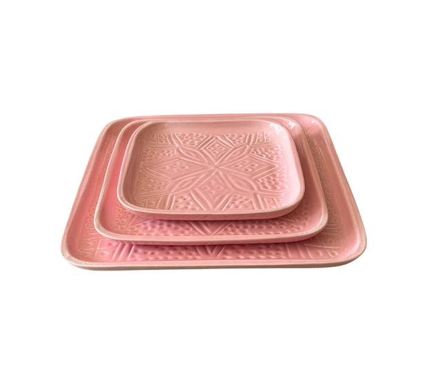 Set of three pink trays with geometric patterns on a white background