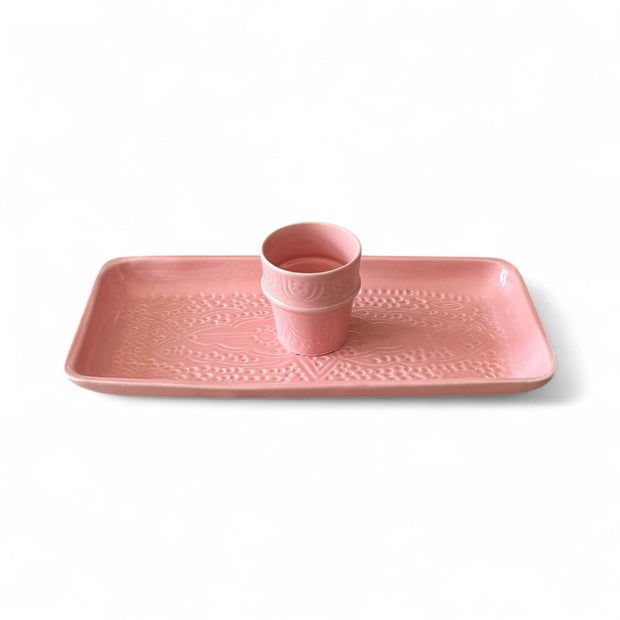 Pink ceramic tray with a matching cup on a white background