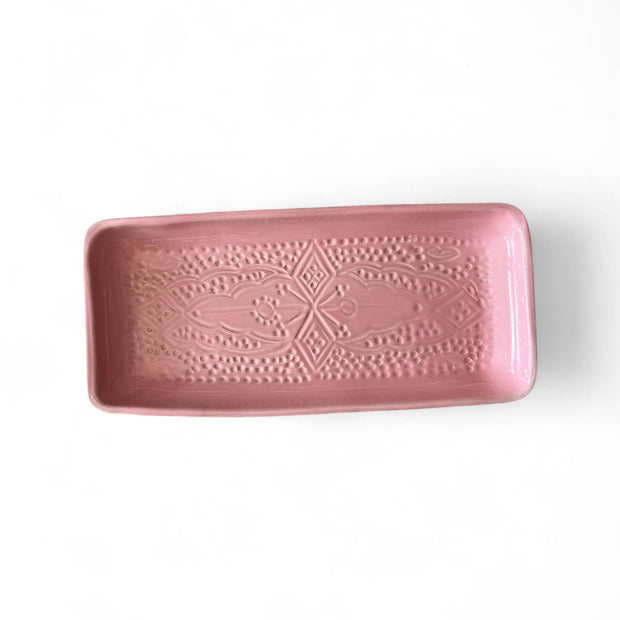 Pink ceramic tray with decorative patterns on a white background