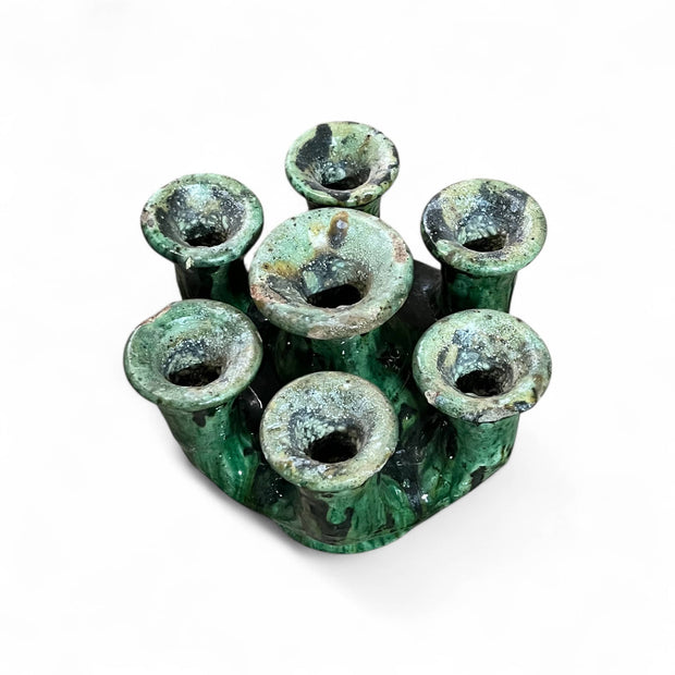 Green ceramic holder with multiple small holes on a white background