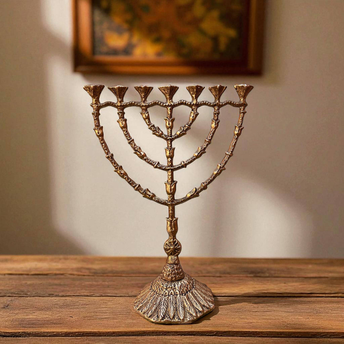 Bronze Menorah on a wooden surface with a blurred painting in the background