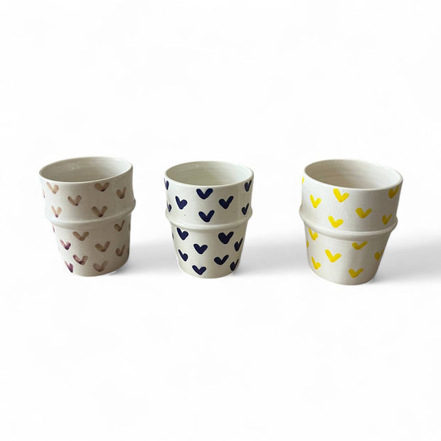 Three stacked ceramic cups with heart patterns on a white background
