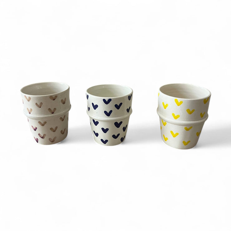 Three stacked ceramic cups with heart patterns on a white background