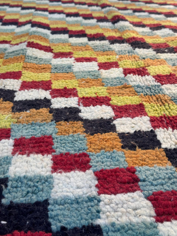 Multicolored checkered patterned rug with various colors.