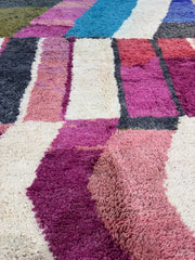 Close-up of a textured rug with geometric pattern in various colors.