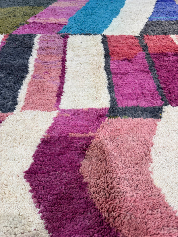 Close-up of a textured rug with geometric pattern in various colors.