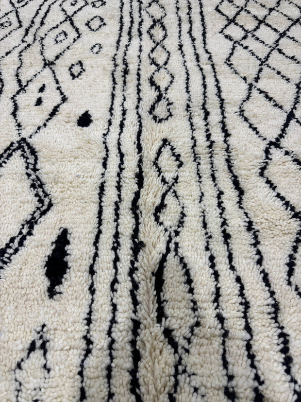Close-up of a textured rug with black geometric patterns on a white background