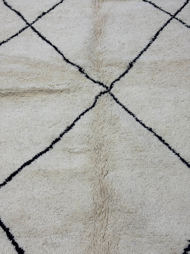 Handwoven Moroccan Azilal carpet in ivory wool with minimalist black diamond pattern and fringe, 246 × 178 cm