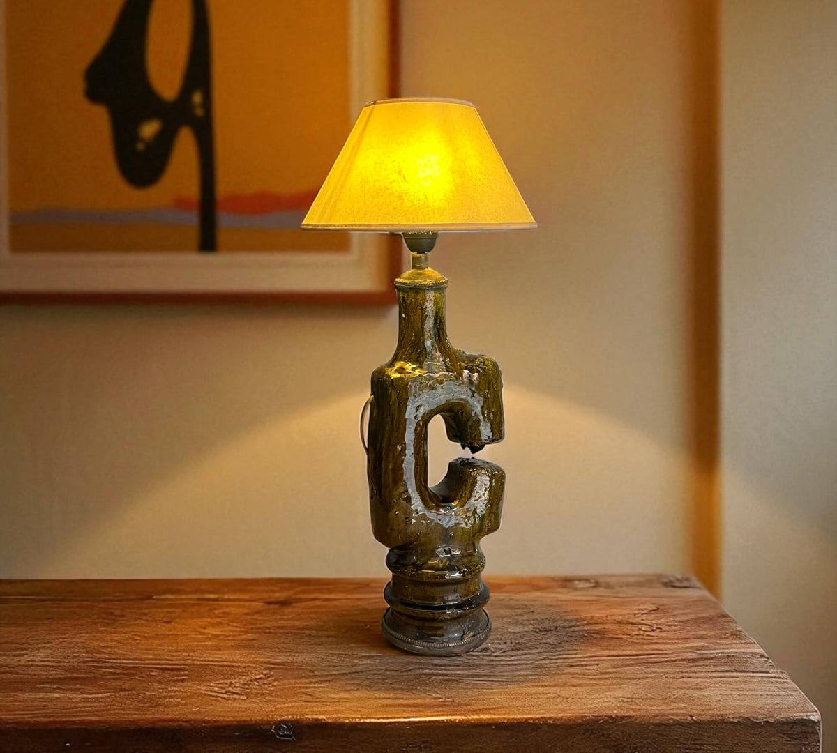 Decorative table lamp with a letter 'C' on a wooden surface, warm lighting.