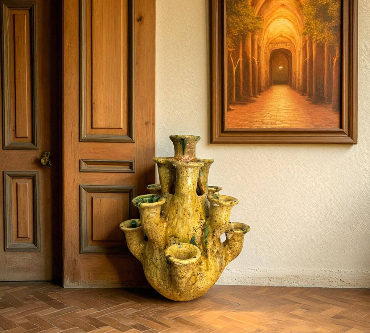 Decorative yellow vase on a wooden floor with a painting of a tunnel in the background.