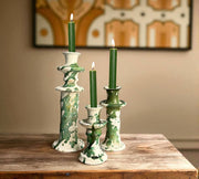 Set of green and white ceramic candle holders with lit candles on a wooden surface.