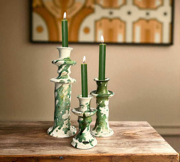 Set of green and white ceramic candle holders with lit candles on a wooden surface.