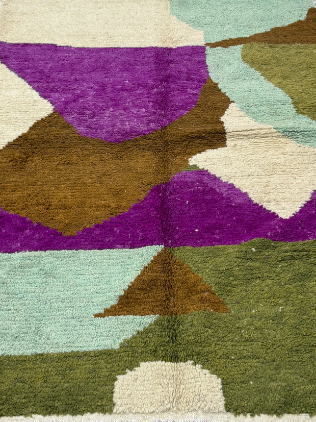 Multicolored geometric patterned rug with purple, brown, green, and beige colors.