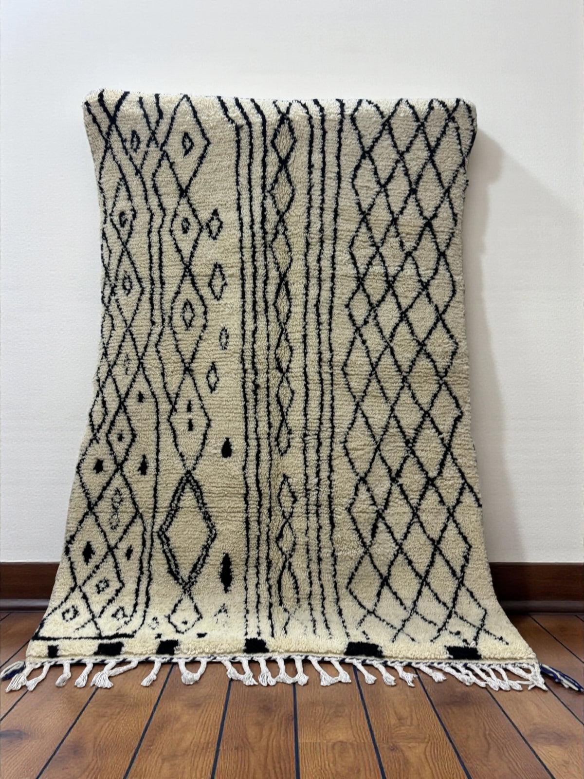 Handwoven Moroccan Azilal carpet in ivory wool with black diamond patterns and fringe, 223 × 156 cm