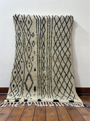 Handwoven Moroccan Azilal carpet in ivory wool with black diamond patterns and fringe, 223 × 156 cm