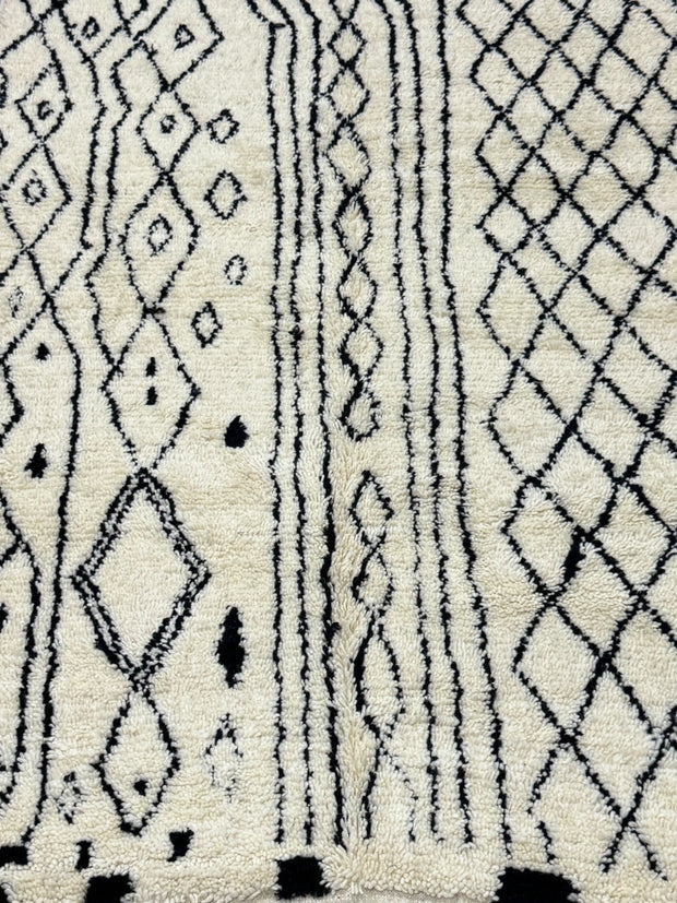 Handwoven Moroccan Azilal carpet in ivory wool with black diamond patterns and fringe, 223 × 156 cm