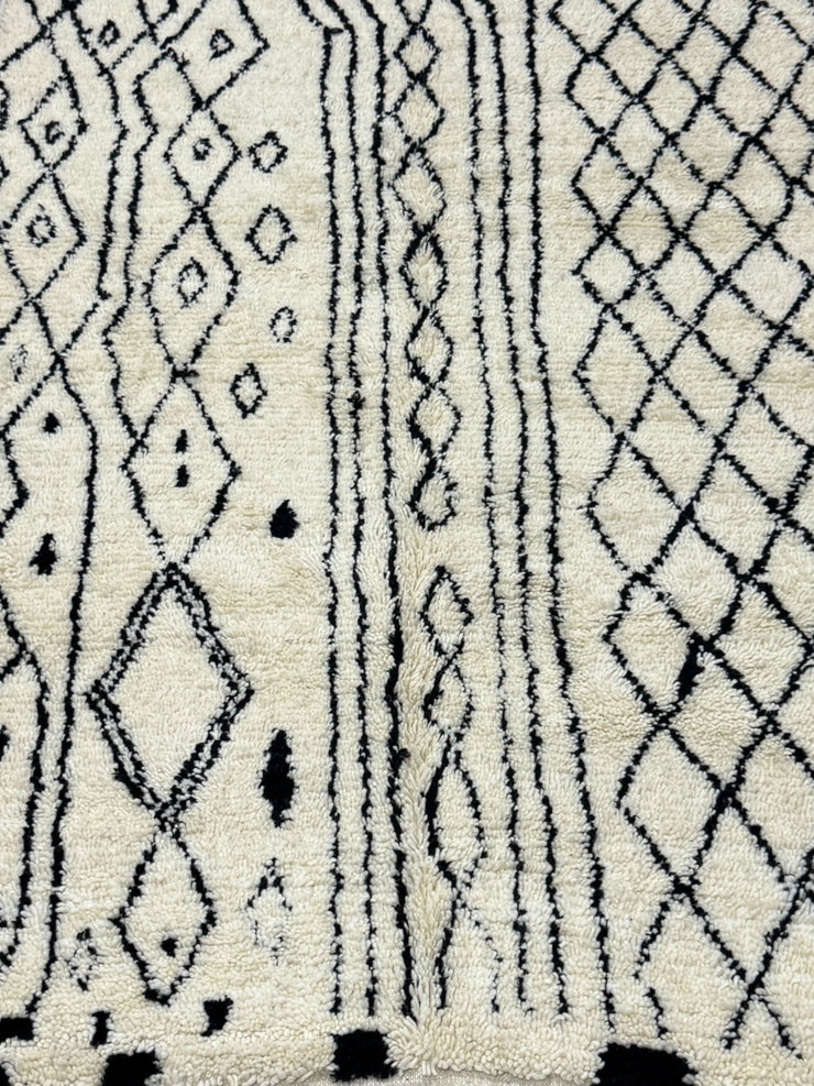 Handwoven Moroccan Azilal carpet in ivory wool with black diamond patterns and fringe, 223 × 156 cm