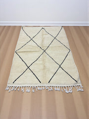 Handwoven Moroccan Azilal carpet in ivory wool with minimalist black diamond pattern and fringe, 246 × 178 cm