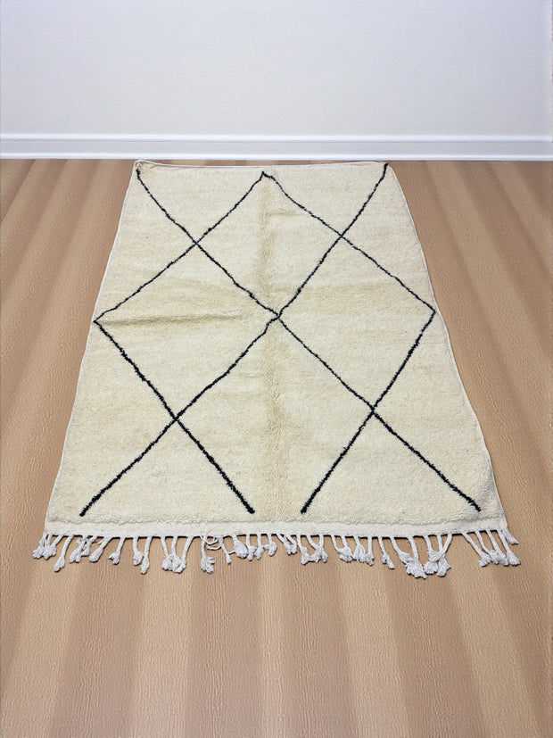 Handwoven Moroccan Azilal carpet in ivory wool with minimalist black diamond pattern and fringe, 246 × 178 cm