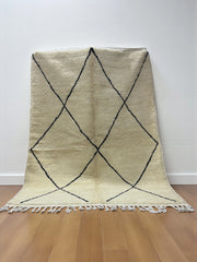 Handwoven Moroccan Azilal carpet in ivory wool with minimalist black diamond pattern and fringe, 246 × 178 cm