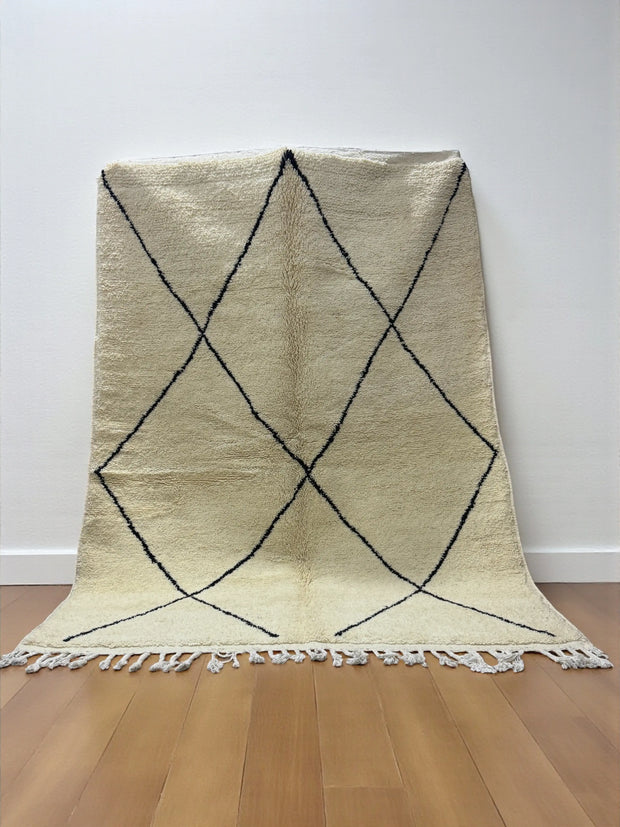 Handwoven Moroccan Azilal carpet in ivory wool with minimalist black diamond pattern and fringe, 246 × 178 cm