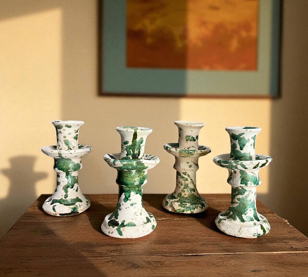 Four ceramic candle holders with green and white marbled pattern on a wooden surface.