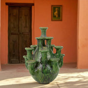 Multi-Neck Vase & Candle Holder against an orange wall with a wooden door.