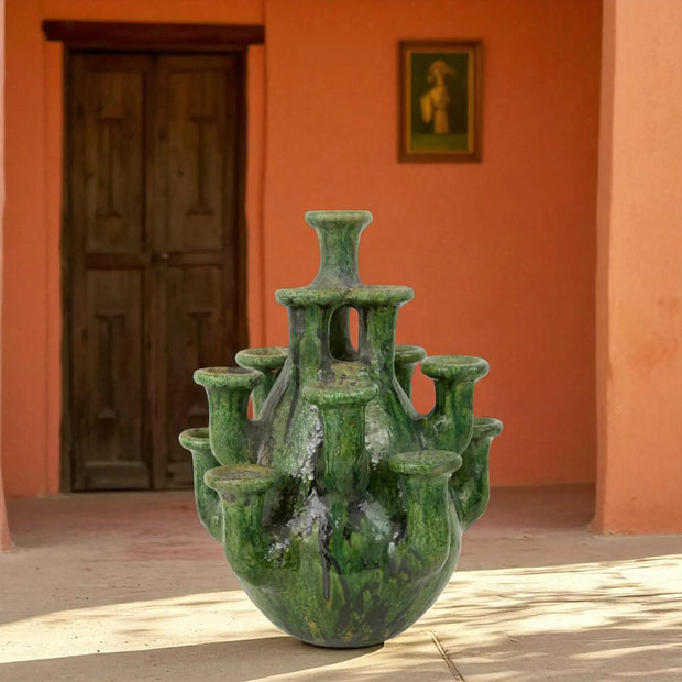 Multi-Neck Vase & Candle Holder against an orange wall with a wooden door.