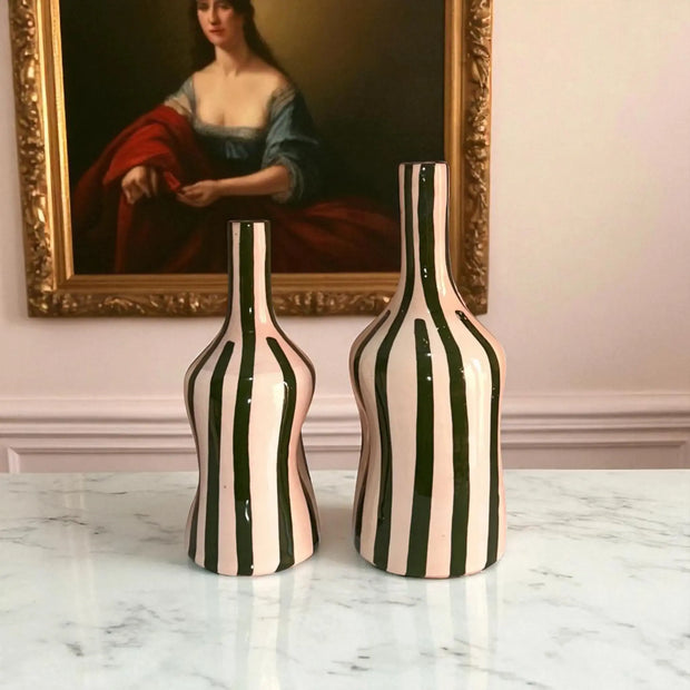 Two striped vases on a marble surface with a painting in the background