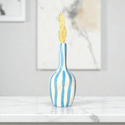 Decorative vase with blue and white stripes and a gold leaf on a marble surface.