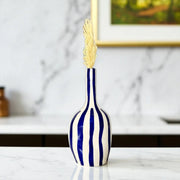Blue and white striped vase with a gold leaf on a marble surface