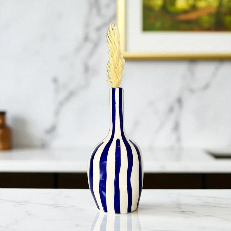 Blue and white striped vase with a gold leaf on a marble surface