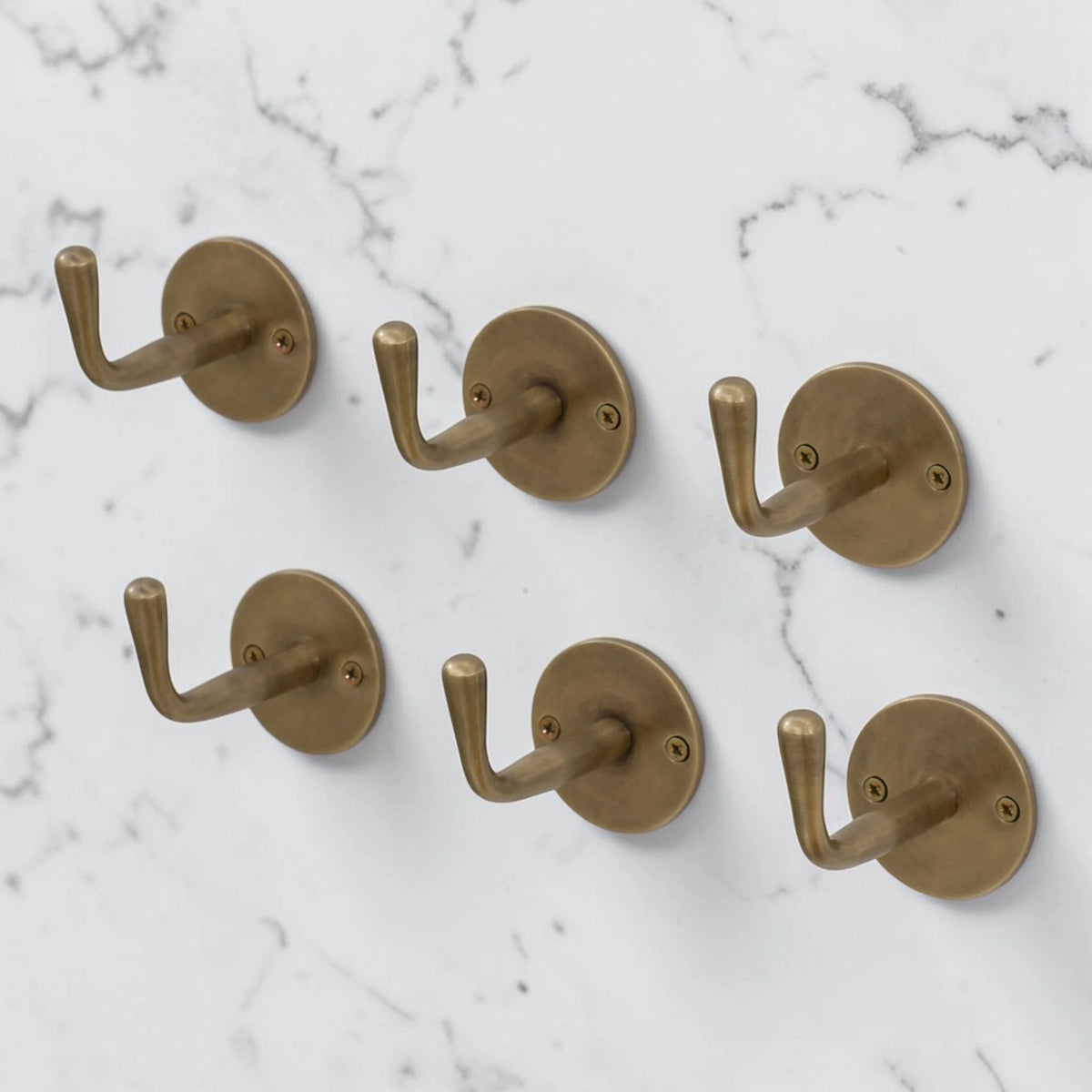 Set of six brass hooks on a marble wall