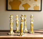 Set of five gold and white ceramic candle holders on a wooden surface with a neutral background.