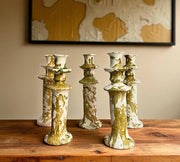 Set of five ceramic candle holders with gold and green glaze on a wooden surface.