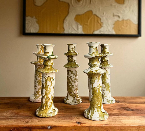 Set of five ceramic candle holders with gold and green glaze on a wooden surface.