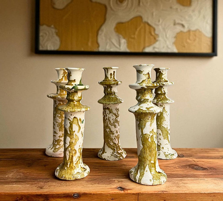 Set of five ceramic candle holders with gold and green glaze on a wooden surface.