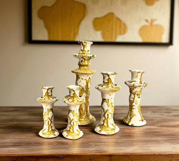 Set of gold and white candle holders on a wooden surface with a neutral background