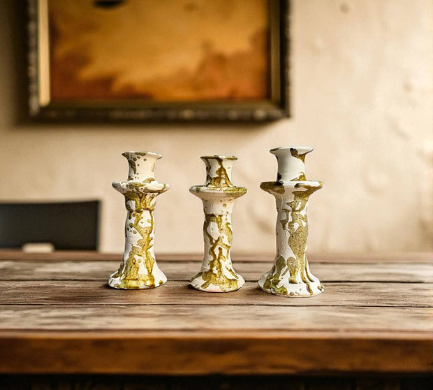 Three decorative candle holders on a wooden surface with a blurred background