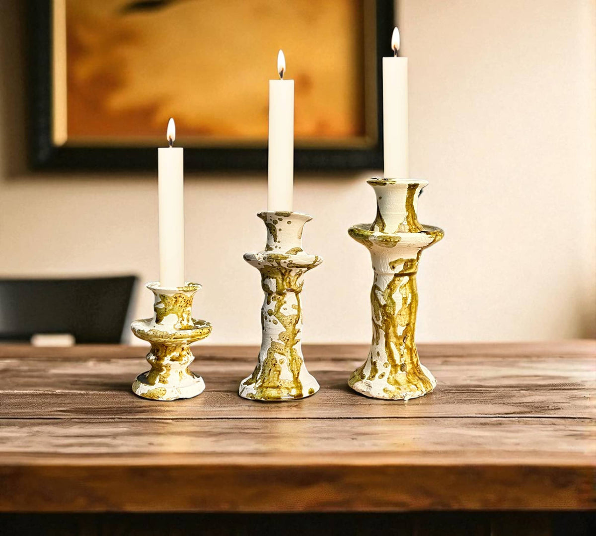 Gold candle holders with white candles on a wooden surface