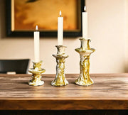Gold candle holders with white candles on a wooden surface