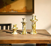 Set of gold and white candle holders on a wooden table with a blurred background