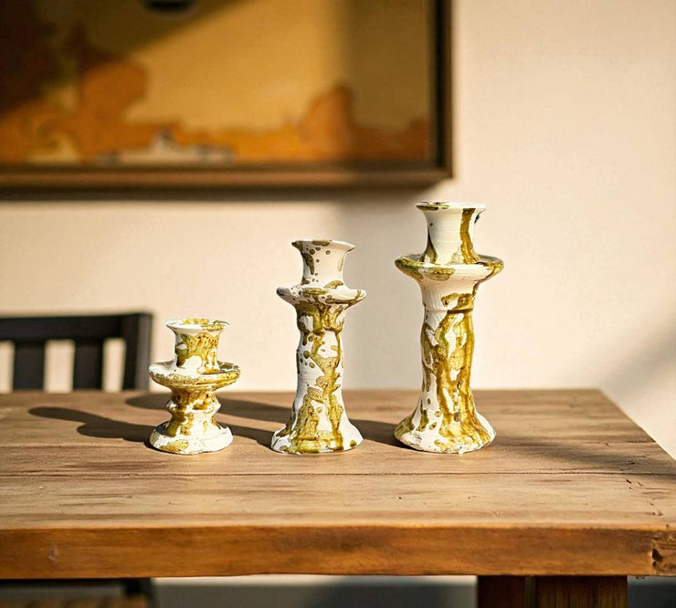 Set of gold and white candle holders on a wooden table with a blurred background